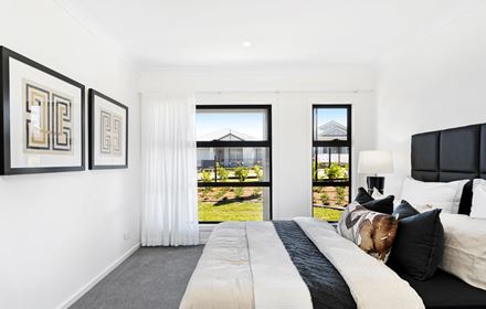 Side on view of a bedroom in the Ellerton 223 display home with bed parallel to windows