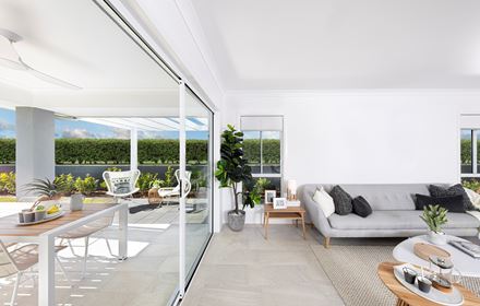 View of the living area in the Lucia One display home parallel to floor to ceiling windows opening up to the outdoor alfresco area