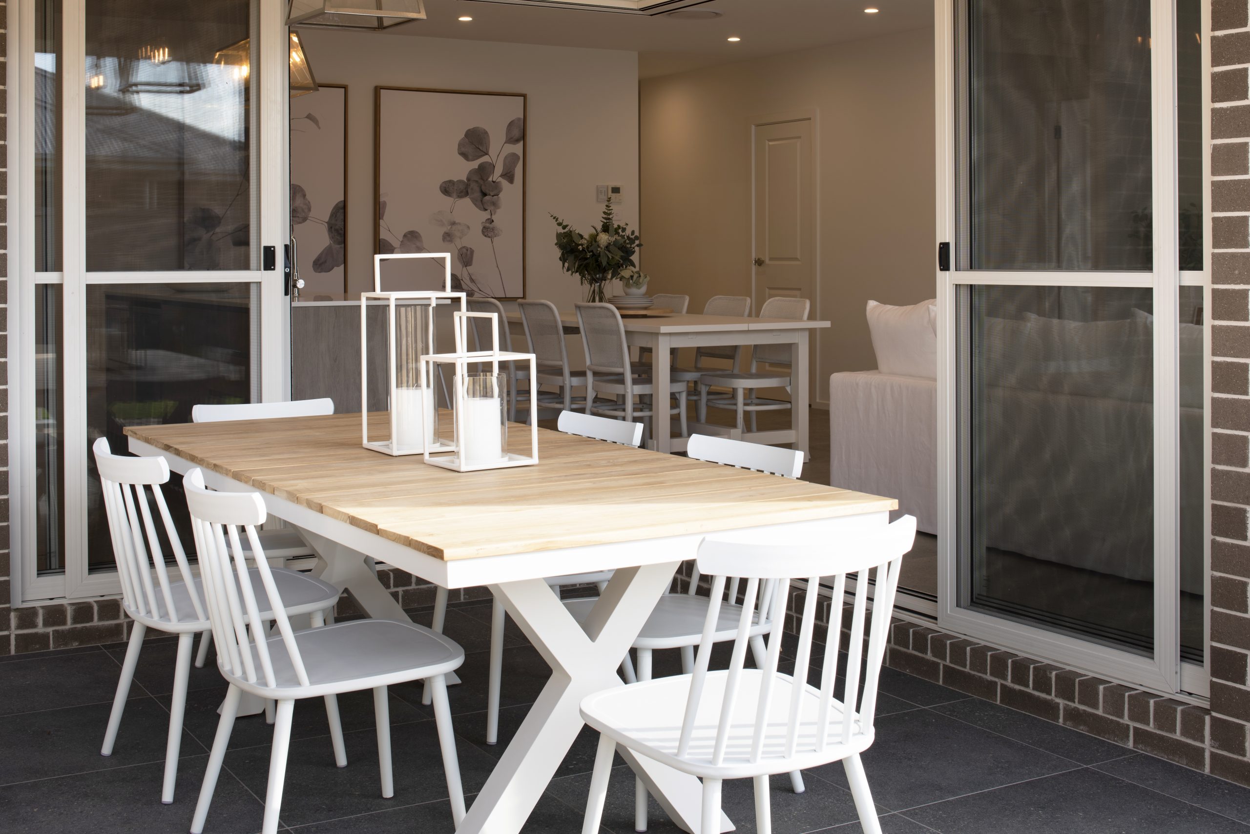 Close up of the outdoor dining table with view into the indoor dining and living areas of the Avalon 220 display home