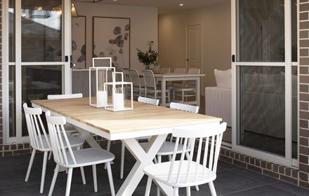 Close up of the outdoor dining table with view into the indoor dining and living areas of the Avalon 220 display home