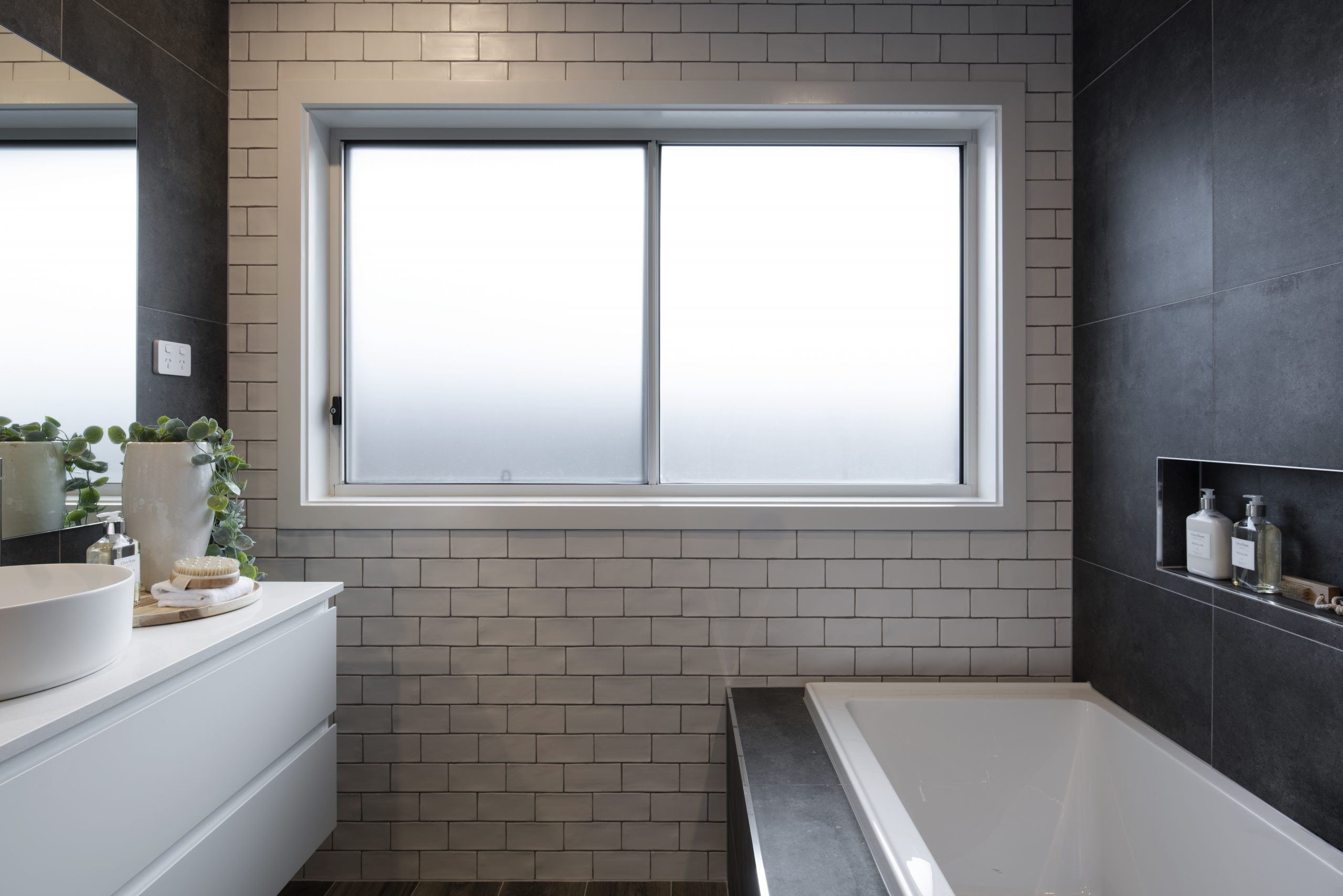 Close up view of a portion of a bathroom  in the Avalon 220 display home showing vanity across from built in bathtub