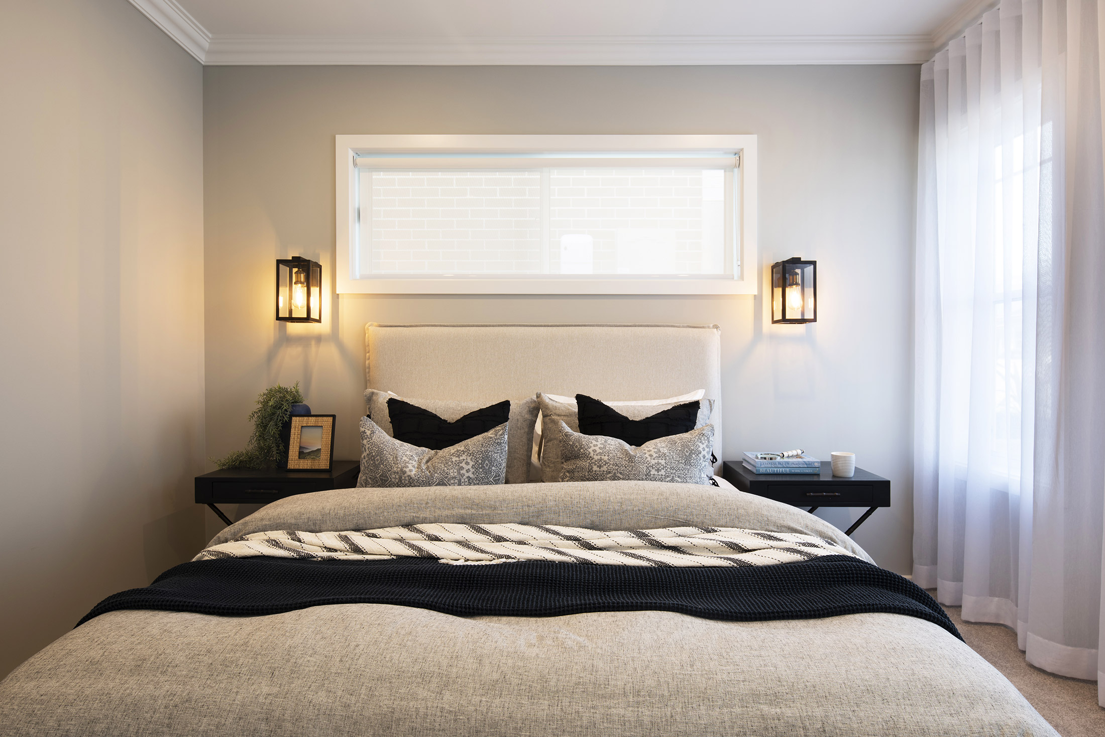 Bedroom in the Avoca display home with bed resting against a light grey wall with clerestory window