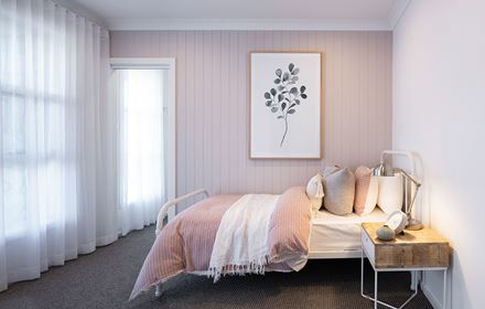 A bedroom styled as a kids room in the Avalon 220 display home with sinle bed against a pink panelled wall