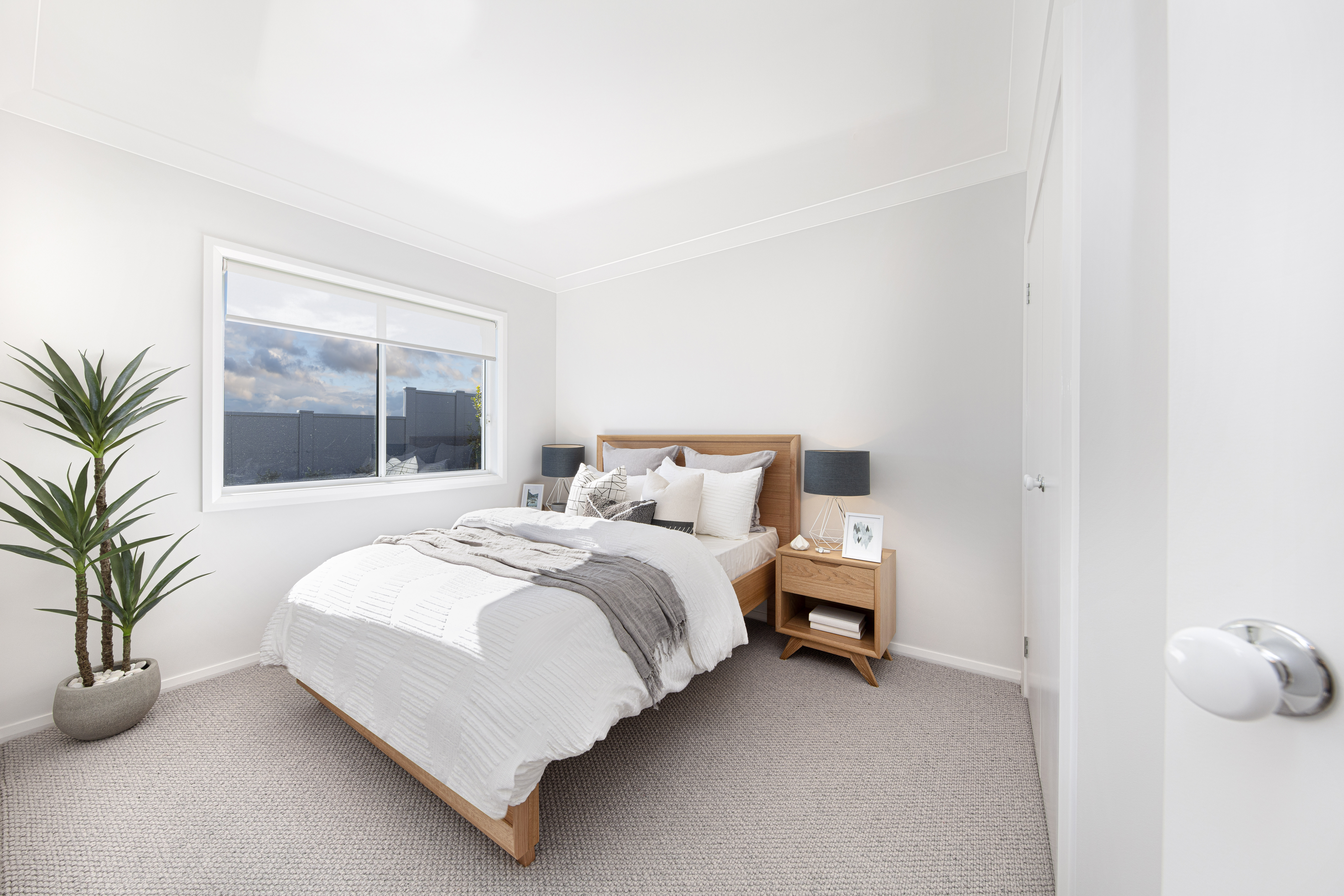 Minor bedroom in the Lucia One display home showing double bed and bedsides parallel to wardrobe doors