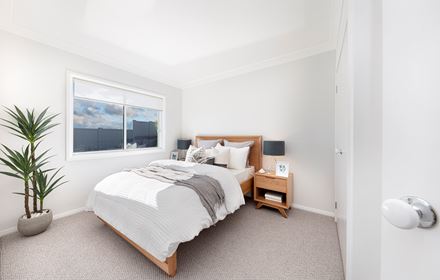 Minor bedroom in the Lucia One display home showing double bed and bedsides parallel to wardrobe doors