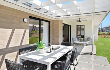 Backyard in the Ellerton 223 display home with paved dining area leading to concrete slab with seats both parallel to a grassed area