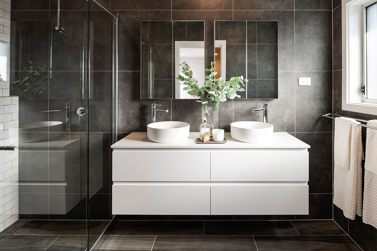 Dark grey tiled ensuite bathroom in the Avalon 220 display home with white double vanity to the right of the shower