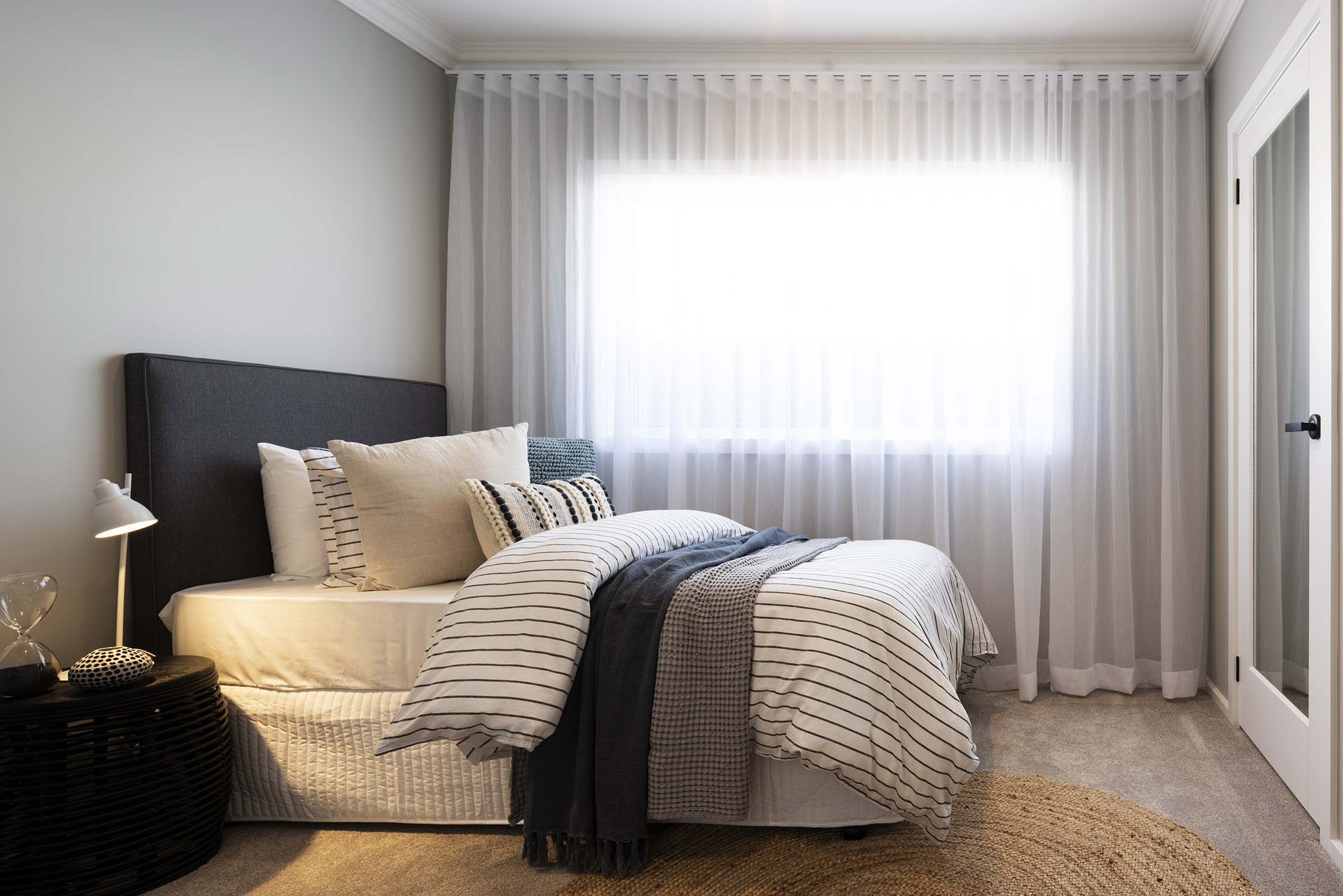 A minor bedroom in the Avoca display with bed and single bedside facing mirrored wardrobe door