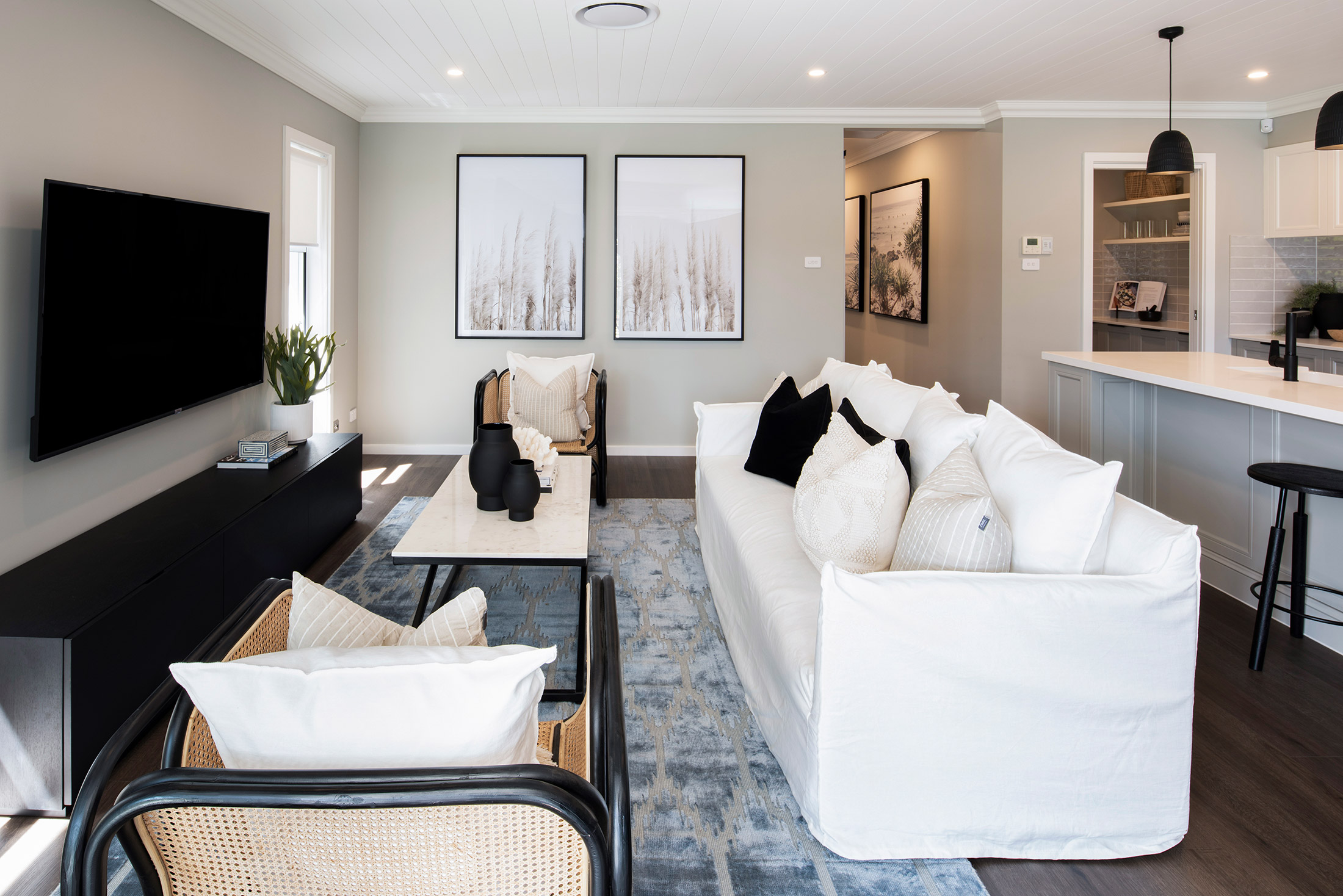 A close up view of the living area in the Avoca display with white linen couch facing low black TV unit and wall mounted TV