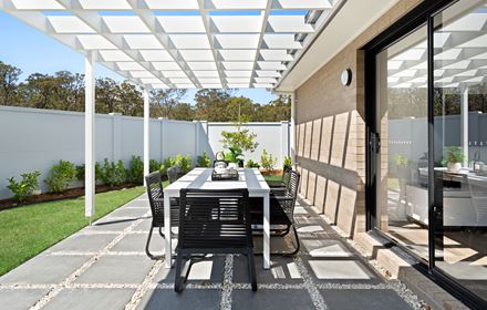 Paved area with outdoor dining table surrounded by grass in the Ellerton 223 display home