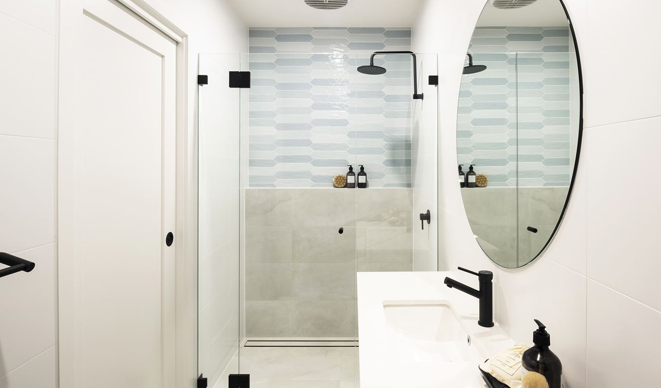 View of a right hand sided single sink below a circular mirror and facing the shower in the Avoca display home