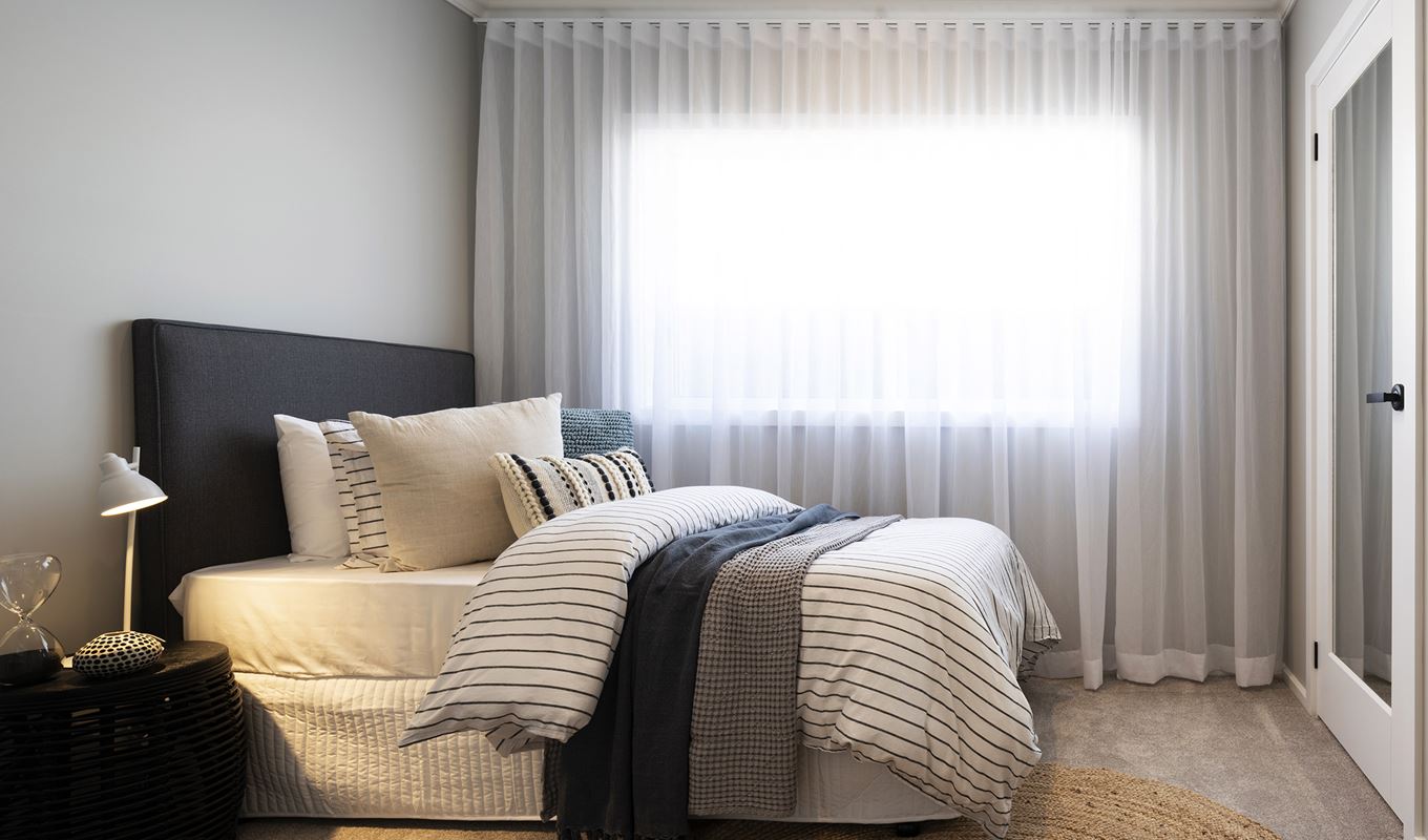 A minor bedroom in the Avoca display with bed and single bedside facing mirrored wardrobe door